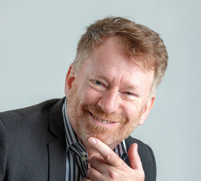 A suited man with a beard smiling. Michael Fairweather, businessman, entrepreneur, author, speaker & facilitator