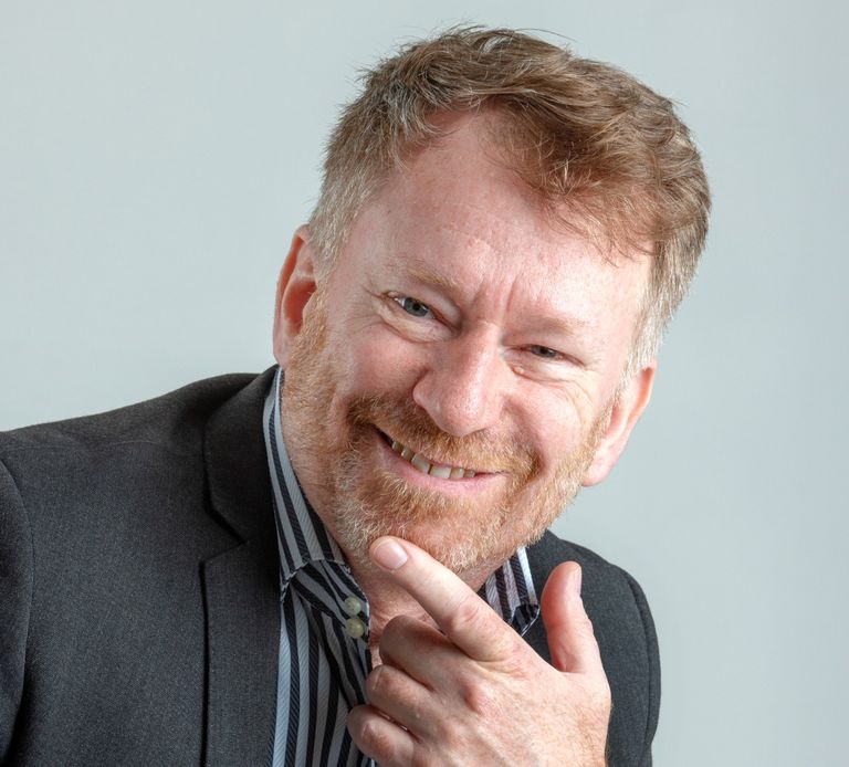 A suited man with a beard smiling. Michael Fairweather, businessman, author, speaker & facilitator.