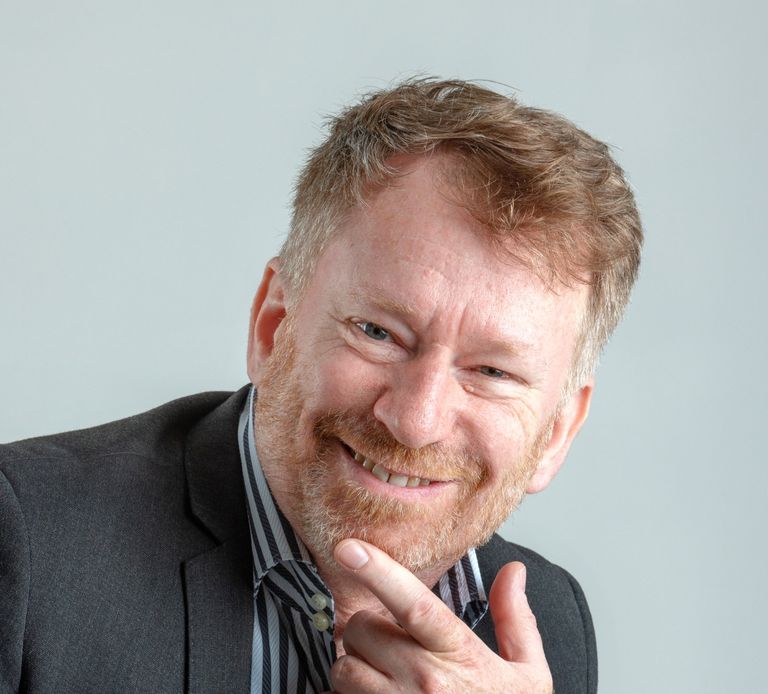 A suited man with a beard smiling. Michael Fairweather, businessman, author, speaker & facilitator.